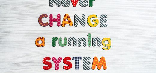 Inspirational quote "Never change a running system" in vivid letters on a wooden surface.